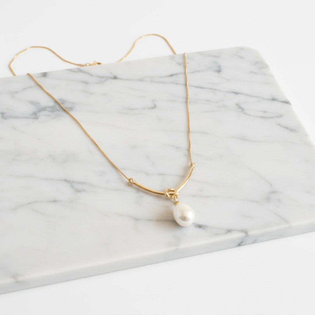 Colar Zynelle Ouro Pérola Nó – Elegância Entrelaçada